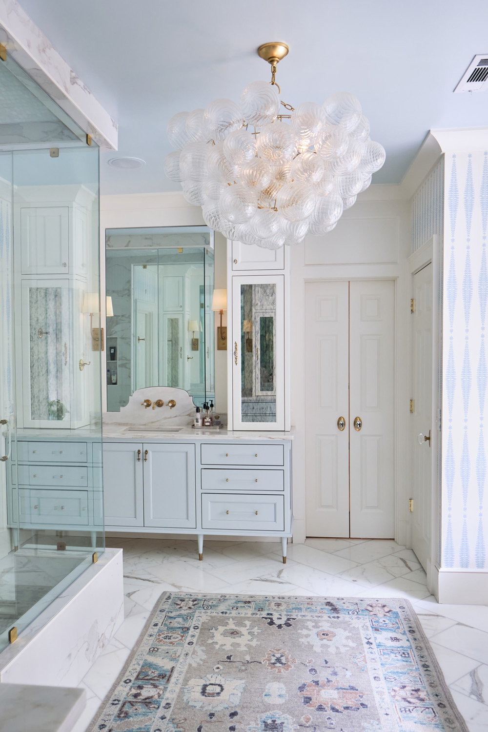 a mid century modern globe chandelier completes the bright white and light blue primary bathroom