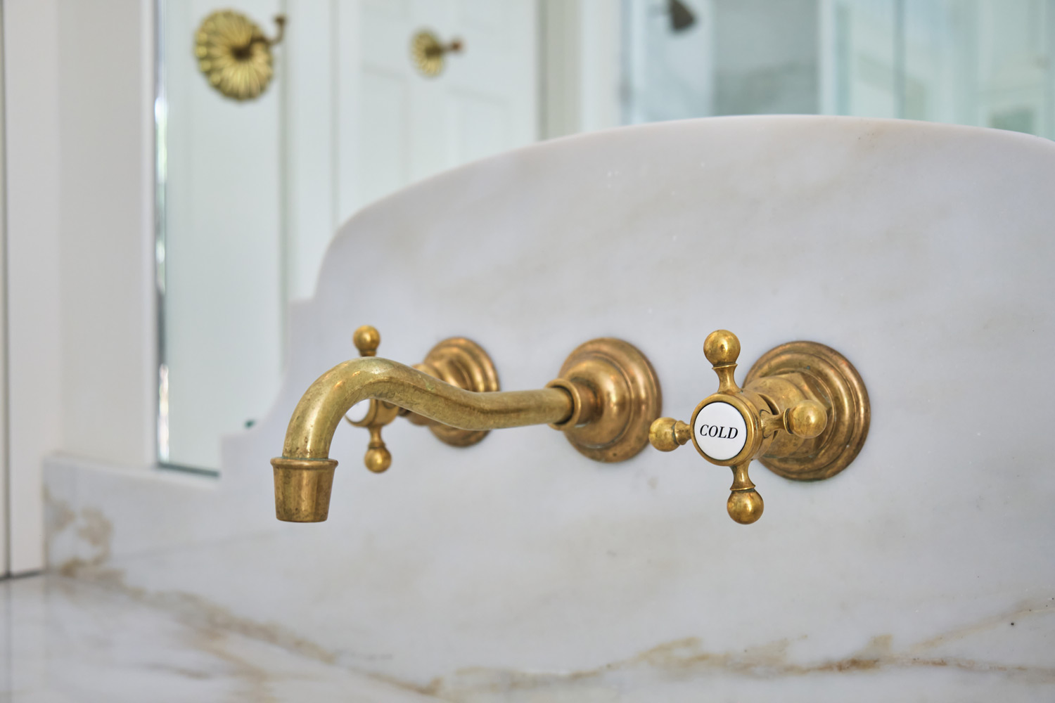 a traditional brass faucet with white porcelain hot and cold valves
