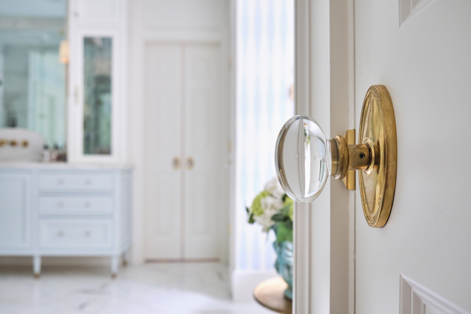 a glass knob with brass trim on the door to the primary bathroom matches the shower door handle