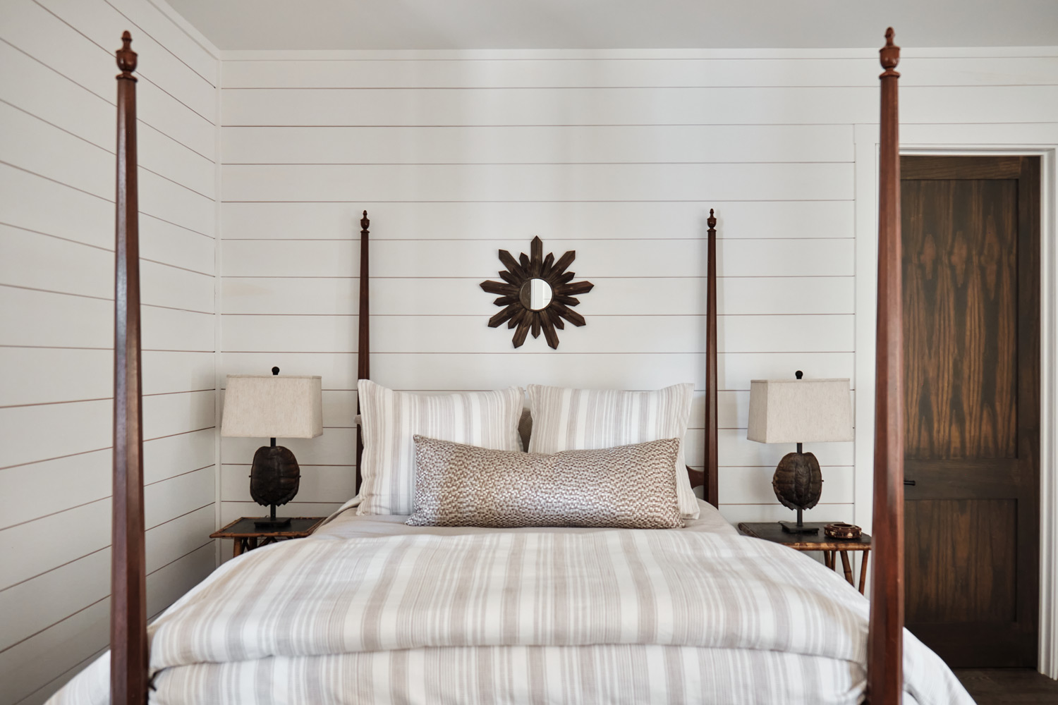 a dark bed frame contrasts the white shiplap walls