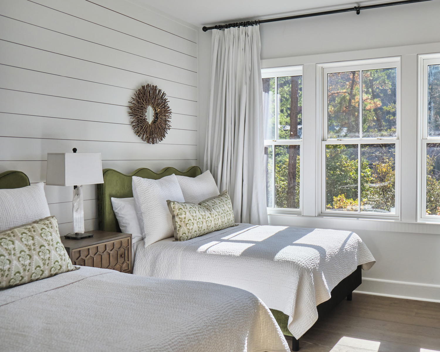a bright and airy bedroom with double beds and white shiplap on the walls
