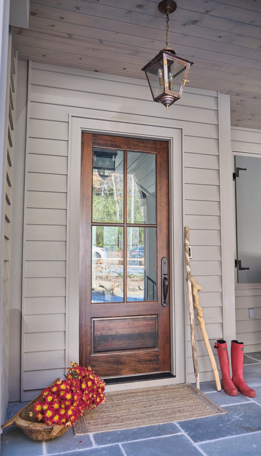 the front door with slate porch floor and a unique brass lantern above