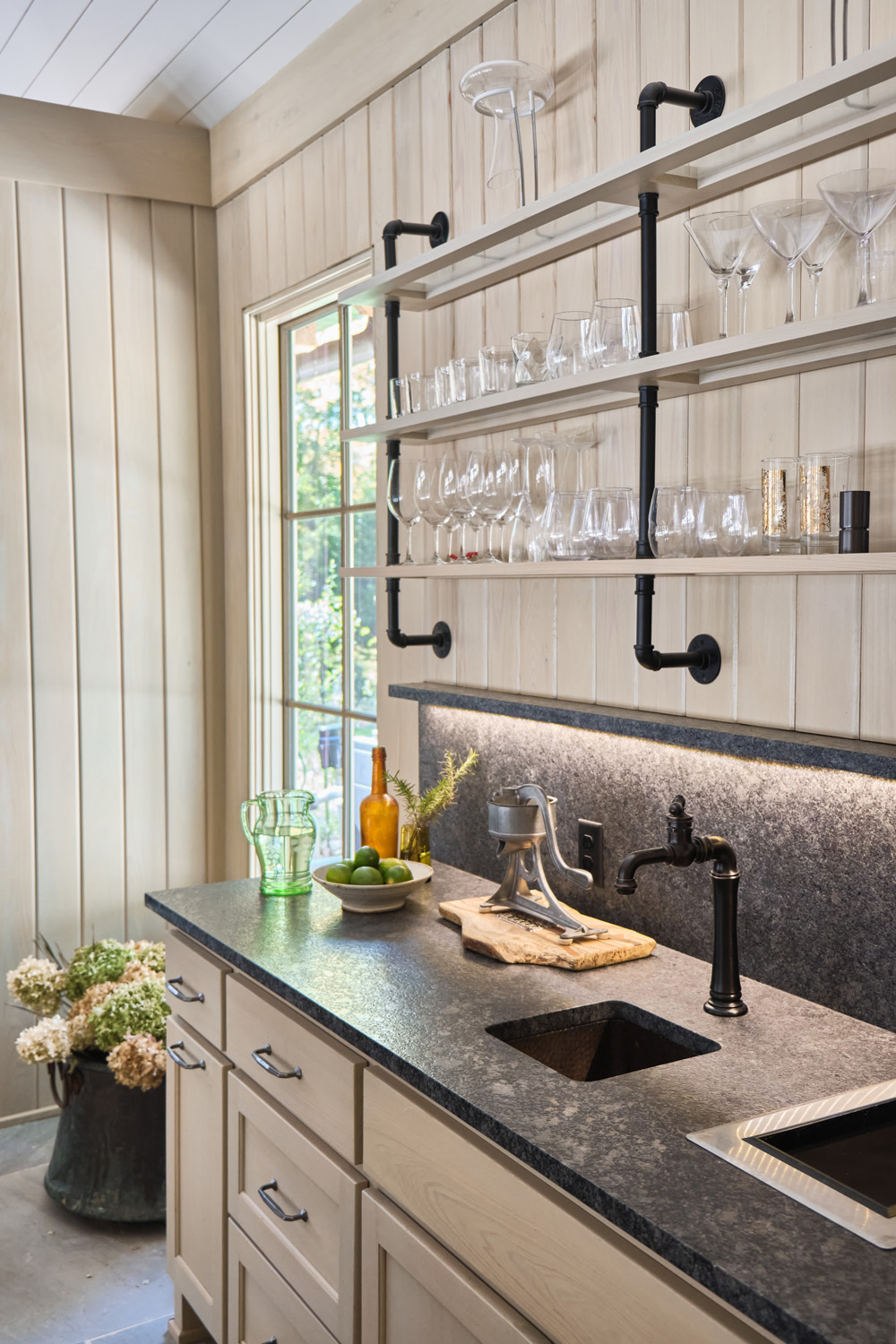 the bar in the pool house with industrial pipe shelves and LED strip lighting